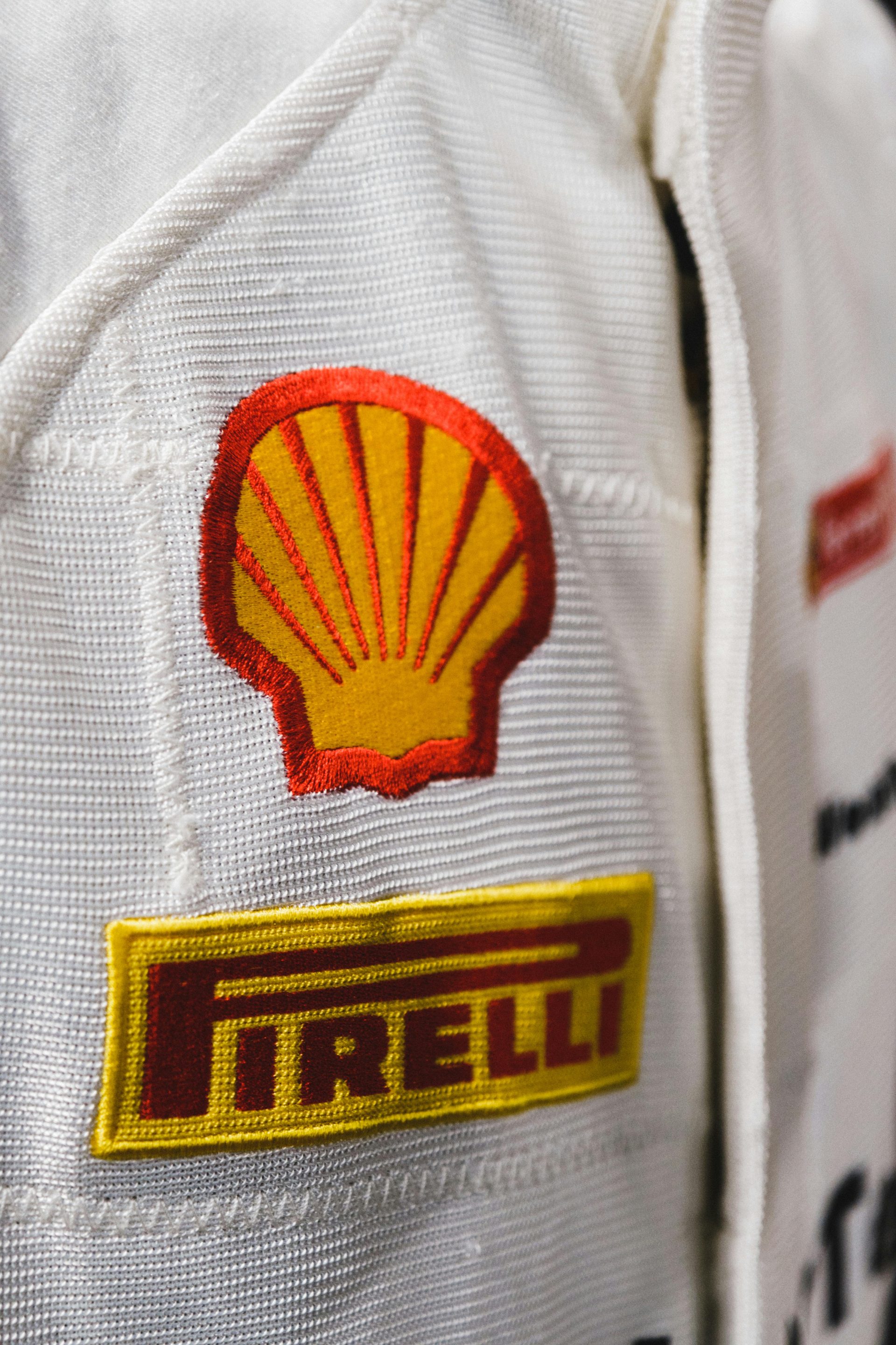 Detailansicht eines Rennanzugs mit den Markenlogos von Shell und Pirelli.